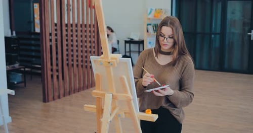 Young Woman Painting on Canvas in Art Studio