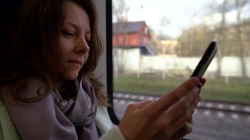 Passagierin der S-Bahn benutzt Smartphone, sitzt neben Fenster, Portrait