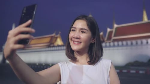 Woman Taking Selfie at Asian Temple at Night