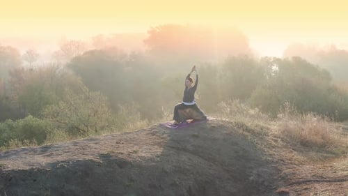 Yoga-Mädchen praktiziert Pilates auf dem Gipfel des Hügels