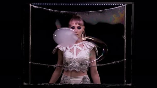 Woman Blowing Iridescent Bubbles in Black Environment