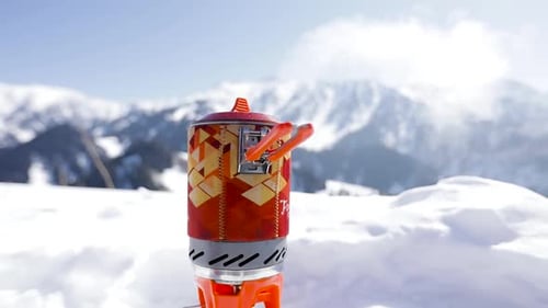 Camping Stove Heating in Snow-Covered Mountain Range