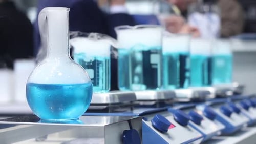 Blue Liquid Bubbling in Laboratory Beakers and Flasks