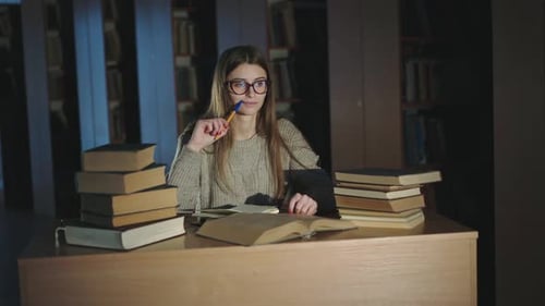 Woman Studying in Dimly Lit Library with Books