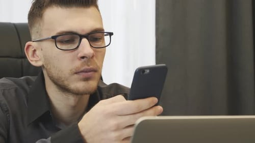 Successful businessman portrait typing on phone sitting at his office desk.