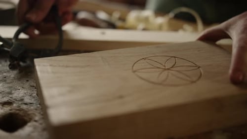Adult Carving Geometric Design on Wooden Plank