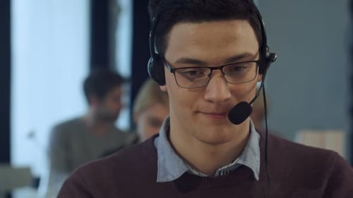 Young Man Working at a Computer in a Call Centre Smiling
