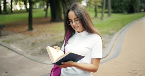 Smiling Student Holding Book on College Campus