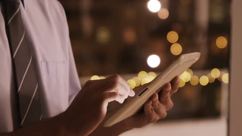 Man Working on Tablet in Corporate Setting at Night