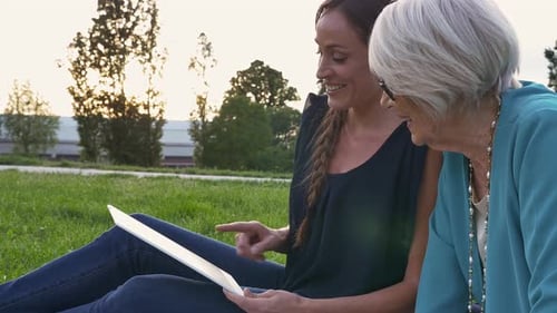 Young Woman and Senior Woman Look at Tablet