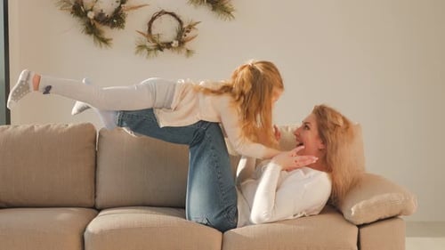 Mother and Daughter Play Airplane on Sofa