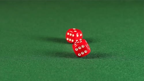 Two red cube rolls and stops on a green table