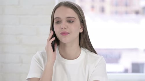 Porträt einer fröhlichen jungen Frau, die auf dem Smartphone spricht