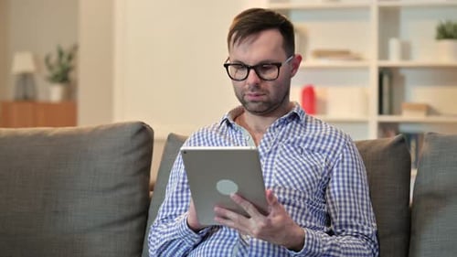Man Using Tablet Device on Couch Indoors
