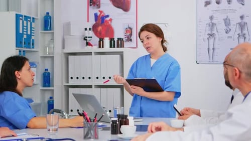 Team of Doctors Discussing Diagnosis Sitting at Table in Clinic
