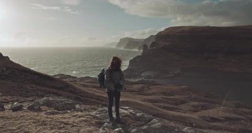 Hiker Stands on Coastal Hilltop Overlooking Ocean