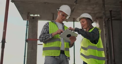 Engineers or Architects Have a Discussion at Construction Site Looking Through the Plan of