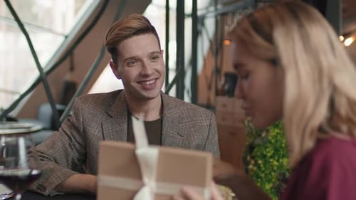 Man Presents Gift to Woman in Restaurant