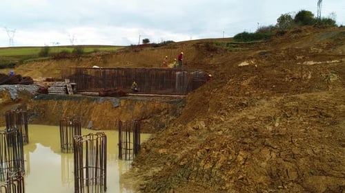 Construction Workers Building Bridge Overpass on Muddy Site