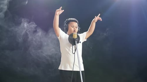Child Sings Into Microphone Wearing Headphones and Raising Arms