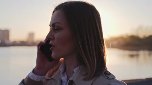 Woman Talking on Phone at Sunset near River