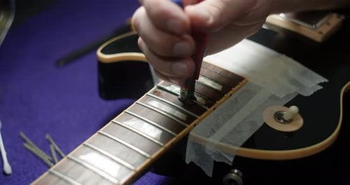 Refretting the Guitar Luthier reemplaza los trastes en el taller de reparación de guitarras eléctricas e instrumentos musicales