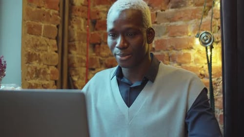 Black Man Talking via Video Call on Laptop in Cafe