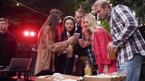 Friends Look at Mobile Phone Outside at Night