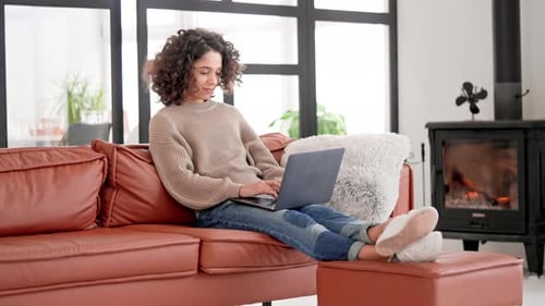 Young Woman Typing on Laptop Sitting on Sofa