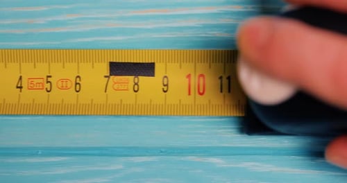 Measuring Tape Being Pulled on Blue Wood