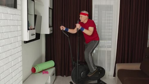 Active Senior Man Exercising on Elliptical Machine at Home