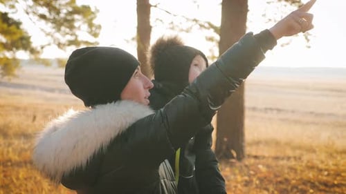 Junge Mutter geht mit einem kleinen Sohn im Herbstwald spazieren