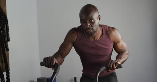 Fit african american man exercising on training bike inside gym
