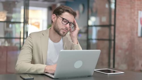 Man Working on Laptop Experiences Headache in Office