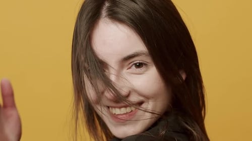Smiling Woman Shakes Head with Flowing Brown Hair