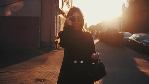 Stylish Woman Walking on City Street at Sunset