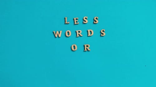 Time Lapse of Quote LESS WORDS MORE ACTION Made Out of Wooden Letters on Bright Blue Background