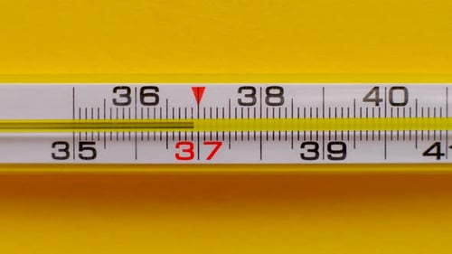 Der Temperaturanstieg wird auf einem Thermometer auf gelbem Hintergrund in Nahaufnahme angezeigt
