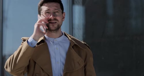 Young Stylish Man in Glasses Talking on Cellphone at the City Street