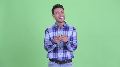 Smiling Man Using Phone Against Green Background