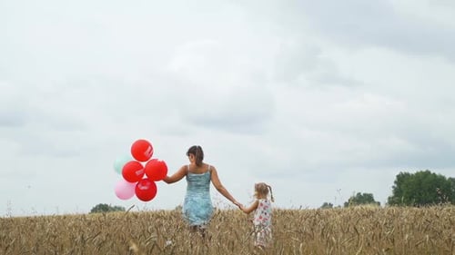 Young Woman with Daughter with Balloons in Field