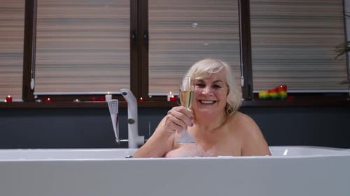 Senior Woman Relaxing with Champagne in Bubble Bath