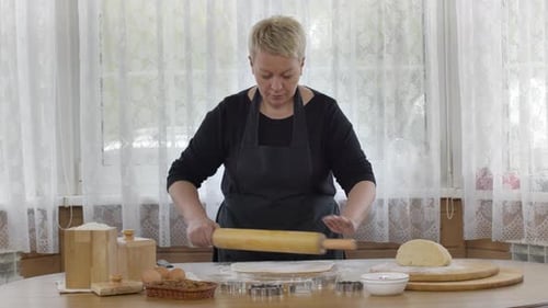 Woman Rolling Out Cookie Dough in Bright Kitchen