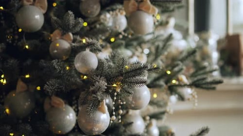 Close Up Shot of Decorated Green Christmas Tree Branch with Shiny Balls and Lights