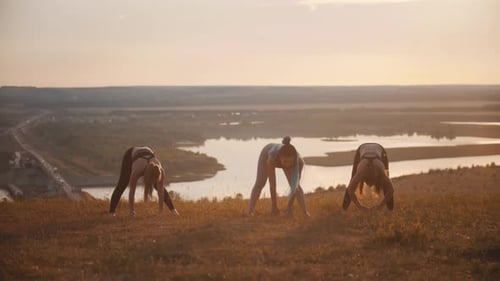 Young Women Exercising on a Hilltop at Sunrise