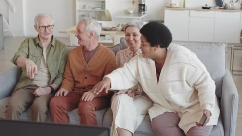 Four Senior Friends Watching Television Together at Home