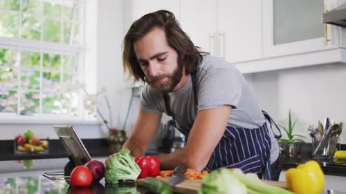 Man With Tablet Prepares Vegetables in Bright Kitchen