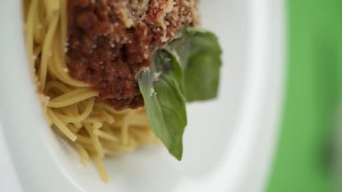 Vertical video: parmesan cheese falls on pasta in a plate