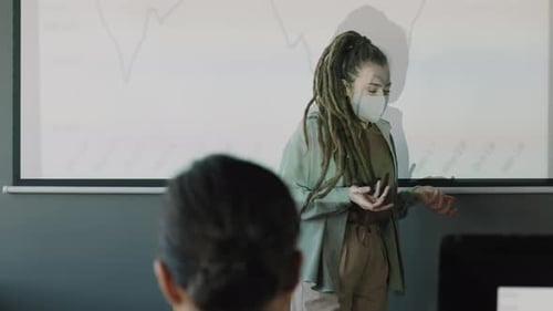 Young Woman Giving Presentation in Office Wearing Mask