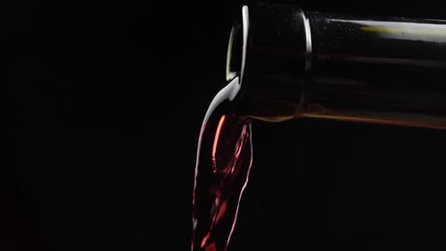 Pouring dark red wine in close up shot